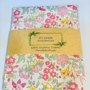 May include: A white cotton handkerchief with a pink and green floral pattern. The handkerchief is folded and wrapped in brown paper with the text "C's Crafts #handmade 100% Organic Cotton Handkerchiefs".