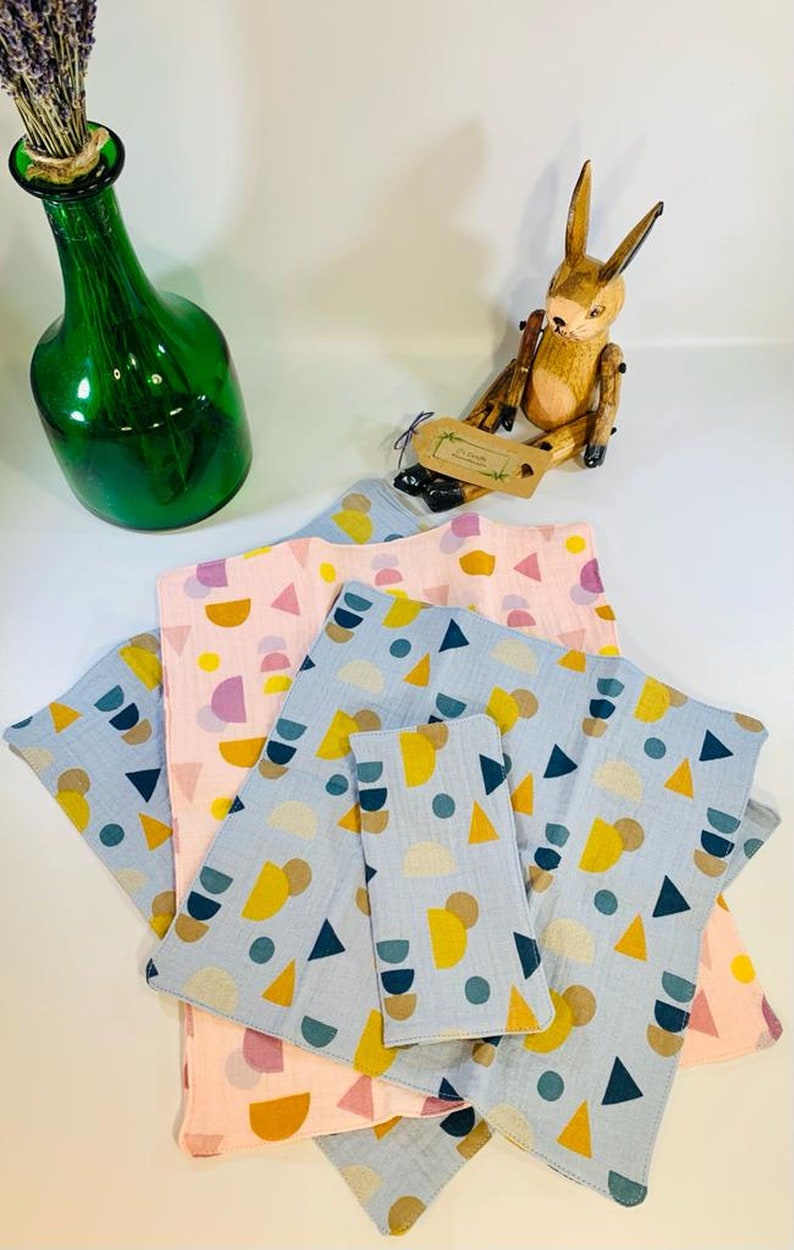 May include: A stack of four blue and pink fabric squares with a geometric pattern of circles, semi-circles, and triangles. The squares are made of a soft, textured fabric and are perfect for a variety of uses, such as cleaning, wiping, or as a decorative element.