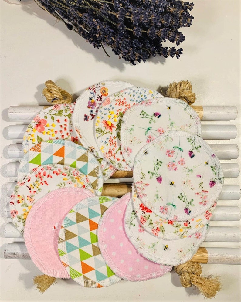 May include: A set of 10 reusable cotton rounds with various floral and geometric patterns. The rounds are white with a white trim and are arranged in a circle on a wooden surface.