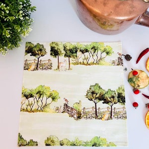 May include: A green and white tea towel with a woodland scene featuring trees, deer, and birds. The tea towel has a stitched border.