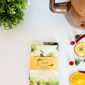 K&ouml;nnte beinhalten: Zwei gr&uuml;ne und wei&szlig;e Baumwolltaschent&uuml;cher mit einem Vogel- und Baumdesign. Die Taschent&uuml;cher sind mit einem gelben Etikett verpackt, auf dem "C's Crafts #handmade 100% Cotton Handkerchiefs" steht.