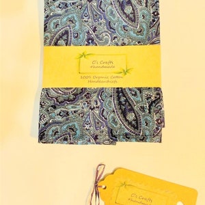 Op de afbeelding: Twee blauwe en paarse paisley-gepatroneerde zakdoeken met een geel label met de tekst "C's Crafts #handmade 100% Organic Cotton Handkerchiefs".