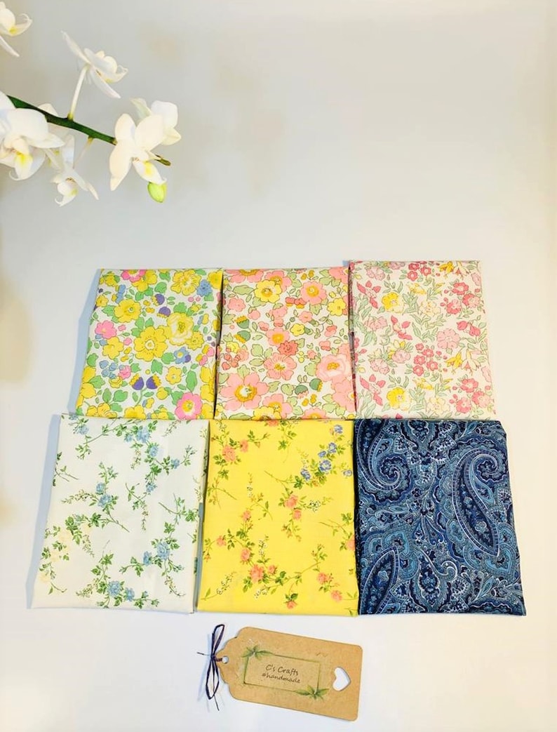 May include: Six fabric squares with different floral and paisley patterns. The fabrics are in shades of yellow, pink, blue, and white. A small brown tag with the text "C's Craft #handmade" is in the bottom right corner.