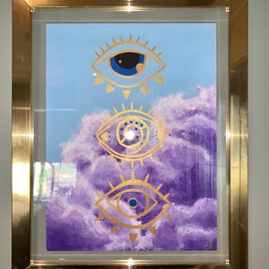 May include: A framed painting with three gold evil eyes on a purple and blue background. The eyes are stylized and have a swirling pattern inside.