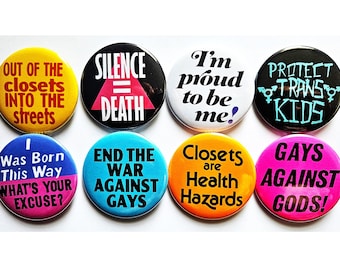 May include: A collection of eight circular pin-back badges featuring diverse slogans. The badges display text including "OUT OF THE CLOSETS INTO THE STREETS," "SILENCE = DEATH," "I'm proud to be me!," "PROTECT TRANS KIDS," "I Was Born This Way," and others.