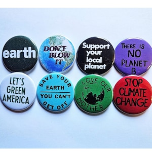 Op de afbeelding: Acht ronde knoppen met verschillende slogans over het milieu erop gedrukt. De slogans zijn: "earth", "Don't Blow It", "Save Your Earth You Can't Get Off", "Support Your Local Planet", "There Is No Planet B", "Let's Green America", "Love Our Mother", en "Stop Climate Change".
