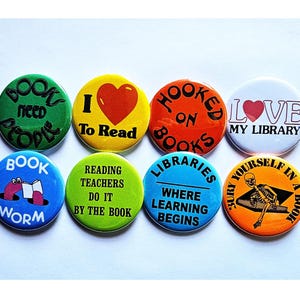 May include: Set of eight round button pins with various book-themed designs. The pins feature colorful backgrounds and black text. Some of the designs include "Book Worm", "I Love To Read", "Hooked On Books", and "Libraries Where Learning Begins".