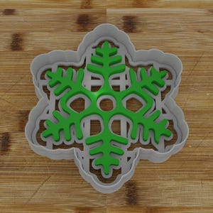 May include: A green snowflake cookie cutter with a detailed design. The cutter is made of metal and has a silver finish.