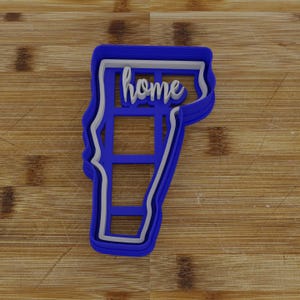 May include: Blue plastic cookie cutter in the shape of the state of Vermont with the word "home" written inside.