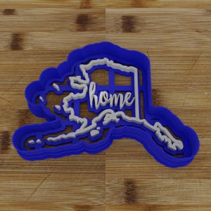 May include: Blue plastic cookie cutter shaped like the state of Alaska with the word "home" inside.