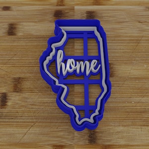 May include: Blue plastic cookie cutter in the shape of the state of Illinois with the word "home" cut out inside.