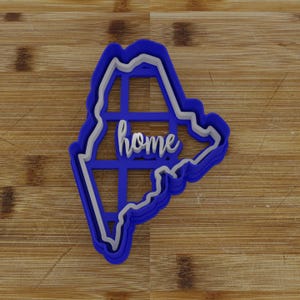 May include: Blue plastic cookie cutter shaped like the state of Maine with the word "home" cut out inside.