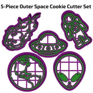 May include: A set of five purple and green outer space-themed cookie cutters. The shapes include a meteor, a spaceship, an astronaut, a globe, and an alien head. The text "5-Piece Outer Space Cookie Cutter Set" is at the top.