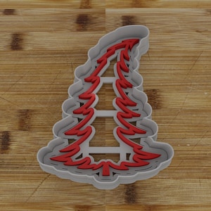May include: A gray plastic Christmas tree cookie cutter with a red outline. The cutter has a detailed design with multiple layers of branches.