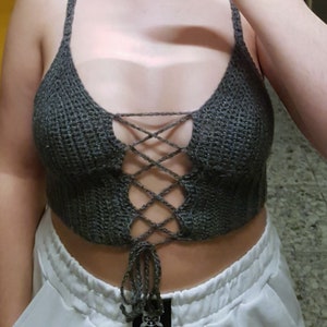 Pode incluir: Um top de crochê cinza com um frente de renda. O top é curto e tem um ajuste solto.