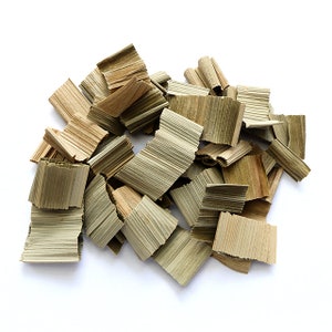 May include: A pile of dried, light brown and green palm leaves, shredded into thin strips. The leaves are arranged in a random pattern on a white background.