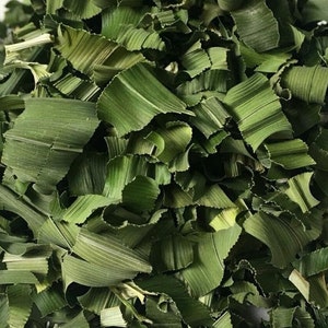 May include: A pile of dried, chopped green leaves. The leaves are a vibrant green color and have a slightly textured surface.