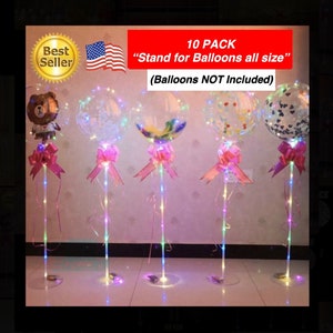 May include: A set of 10 clear balloon stands with LED lights. Each stand has a pink ribbon and a clear balloon. The balloons are not included. The text "10 PACK" and "Stand for Balloons all size" is visible in the image. The text "(Balloons NOT Included)" is also visible in the image.