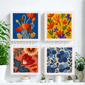 Pode incluir: Quatro peças de arte floral quadradas emolduradas. Cada peça apresenta um design floral colorido diferente, incluindo papoulas, flores abstratas e padrões florais azuis. A obra de arte é exibida em uma parede branca com vegetação.