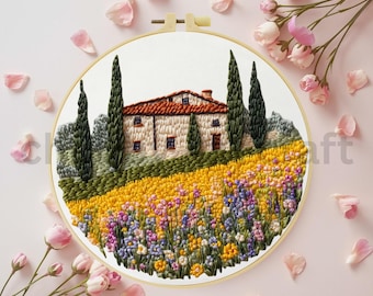 May include: Embroidered landscape art in a round wooden hoop. The artwork depicts a house with a red tile roof, green trees, and a field of yellow, purple, and blue flowers. Pink flower petals and roses surround the hoop.