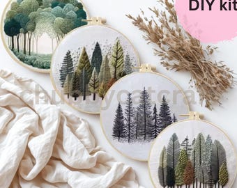 May include: Four embroidery hoops with forest scenes. The designs feature various trees in shades of green, brown, and black. The text "DIY kit" is visible on a pink circle. The hoops are displayed on a white surface with a beige fabric.
