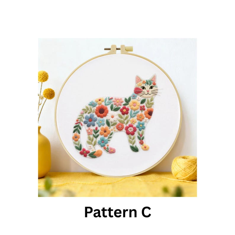 Puede incluir: Dise&ntilde;o de gato bordado en un aro de madera. El gato est&aacute; lleno de flores coloridas en tonos de rojo, naranja, azul y verde. El texto "Pattern C" est&aacute; en la parte inferior de la imagen.