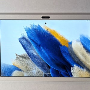 Könnte beinhalten: Ein weißes Tablet mit einem blauen und gelben abstrakten Hintergrund auf dem Bildschirm. Die Uhrzeit ist 18:42.