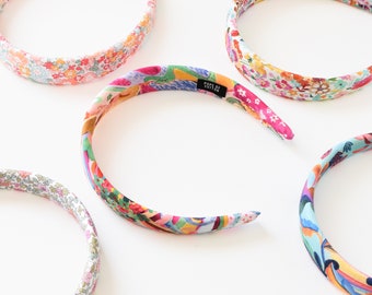 May include: Four colorful floral patterned headbands. The headbands are made of fabric and have a simple design. The headbands are all different colors and patterns.