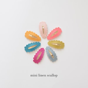May include: A set of eight mini linen scallop hair clips in various colors, including pink, blue, yellow, and green. The clips are arranged in a circle on a white background.
