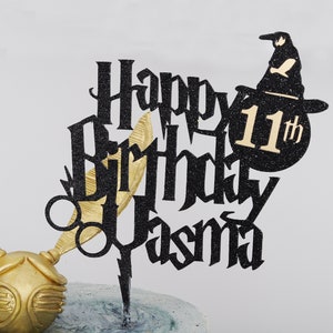 Peut inclure: Décor de gâteau en paillettes noires avec les mots "Happy Birthday" et le nom "Jasna" en police gothique. Le décor comprend également une silhouette noire d'un chapeau de sorcière avec un "11th" en paillettes dorées sur le dessus.