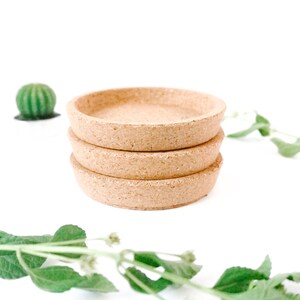 May include: Three stacked cork plant saucers, a light brown color, on a white background. The saucers are round and have a slightly raised edge.