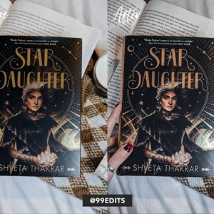 Może przedstawiać: Zbliżenie na książkę zatytułowaną "Star Daughter" autorstwa Shvety Thakrar. Okładka przedstawia kobietę o ciemnych włosach i czarnej sukni, trzymającą świecącą kulę. Tło stanowi ciemne, gwiezdne niebo z złotymi akcentami.