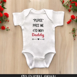 May include: White baby onesie with black text that reads "PLEASE PASS ME TO MY Daddy" with a red heart and arrows on either side.  The text "Daddy" is in red.