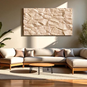 Puede incluir: Un salón moderno con un sofá seccional de color claro con marcos de madera, complementado con una mesa de centro redonda de madera. Una gran obra de arte que se asemeja a papel arrugado cuelga sobre el sofá. Las plantas en macetas añaden un toque natural.