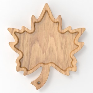 May include: A wooden maple leaf-shaped serving tray. The tray is made of light-colored wood with a natural grain pattern. It features a carved outline and a small handle. The tray is designed for serving food or as a decorative piece.