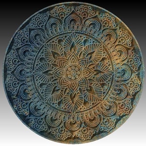 May include: A circular mandala design with intricate details in shades of blue, brown, and gold. The mandala is carved into a round, flat surface, creating a raised, textured pattern.