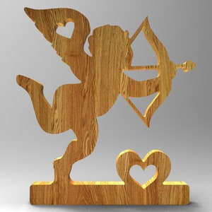 Könnte beinhalten: Holzfigur eines Cupidos mit Pfeil und Bogen, Flügeln und einem herzförmigen Ausschnitt. Der Amor steht auf einem Sockel mit einem Herz-Ausschnitt. Die Holzmaserung ist sichtbar.