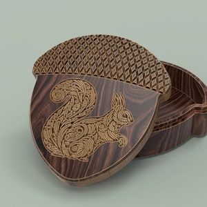 May include: A wooden acorn-shaped box with a detailed squirrel design carved into the lid. The box is open, revealing the interior.