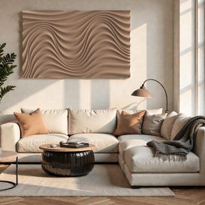 Op de afbeelding: Een moderne woonkamer met een beige hoekbank, kussens en een salontafel. Boven de bank hangt een groot, getextureerd, beige kunstwerk. Een vloerlamp en een plant verfraaien het decor. De kamer heeft een neutraal kleurenpalet.