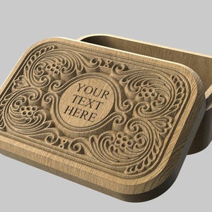 May include: A wooden box with an open lid, featuring intricate carved floral and scrollwork designs. The lid has a central oval area with the text "YOUR TEXT HERE". The box is light brown and sits on a gray background.