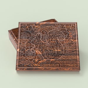 May include: A wooden box with a carved floral design. The box is open and the lid is resting on top of the box.