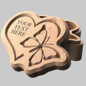 May include: Wooden heart-shaped box with a butterfly design and the text "YOUR TEXT HERE" carved into the lid. The box is made of light brown wood and has a three-dimensional design.