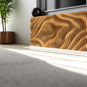Può includere: Un rivestimento per radiatore in legno con un design ondulato e testurizzato. Il rivestimento è realizzato in legno sottile e stratificato e ha un colore marrone chiaro.