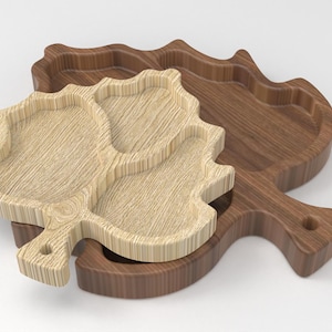 May include: Two wooden leaf-shaped serving trays. One is light-colored, the other is dark brown. The light-colored tray has three compartments. The dark brown tray has a handle with a hole.