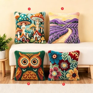 Op de afbeelding: Vier decoratieve sierkussens met kleurrijke ontwerpen. Eén heeft paddenstoelen en kleine huisjes, een ander een lavendelveld, een derde een uil en de laatste een bloemenpatroon. De kussens zijn op een witte bank geplaatst.