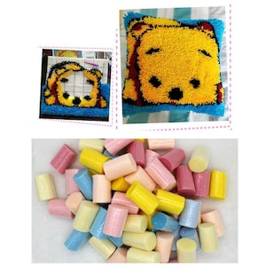 May include: A close-up of a pile of colorful yarn spools, perfect for rug hooking or punch needle projects. The yarn is in various shades of pink, yellow, blue, and white.