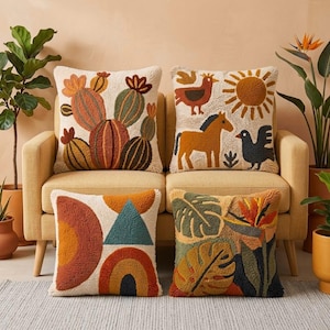 May include: Four decorative throw pillows with textured designs. One features cacti in shades of orange, green, and brown. Another has a horse, bird, and sun. The third has geometric shapes, and the fourth has tropical leaves and flowers. All are on a yellow sofa.