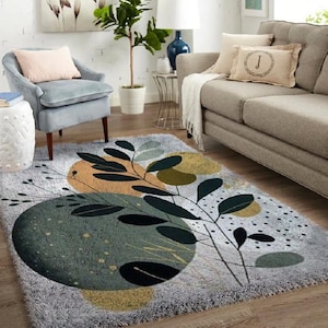 Peut inclure: Un tapis rectangulaire gris à poils longs avec un motif abstrait. Le tapis présente de grands cercles superposés dans des tons de vert, d'or et d'orange, avec des motifs de feuilles et de tiges noires. Le tapis est placé dans un salon.