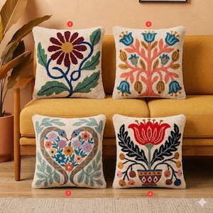 May include: Four decorative throw pillows with embroidered floral designs. The pillows feature a cream-colored background with colorful flowers, leaves, and vines. One pillow has a large red flower, another a tree, a third a heart shape, and the last a flower in a vase.
