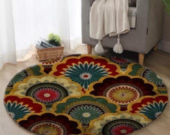 May include: A round area rug with a floral pattern in shades of red, green, yellow, and blue. The rug is placed on a light-colored wooden floor. The rug's design features a repeating motif of stylized flowers.